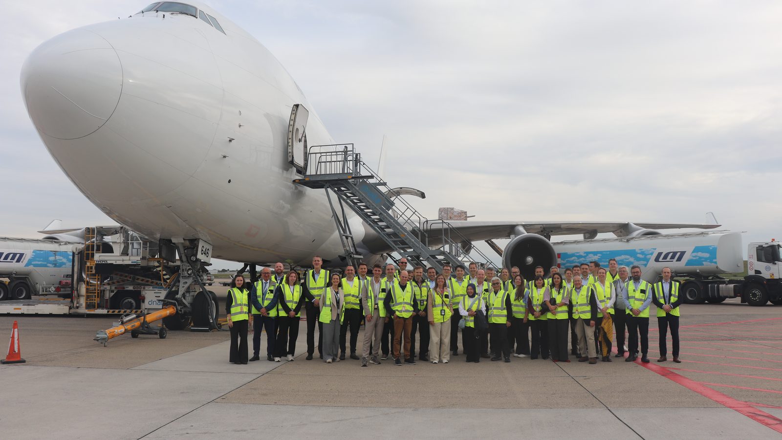 IARO delegates in high-visibility vests lined up on the cargo apron at Brussels Airport, in front of a Boeing 747 freighter with its nose open