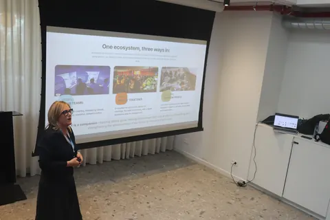 A speaker presents a slide headed 'One ecosystem, three ways in', with three photographs of training sessions