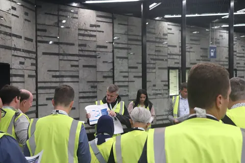 Delegates in high-visibility vests gathered round a guide holding a site map