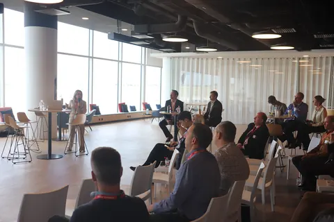 Delegates seated by the windows watch a speaker at the front of the room