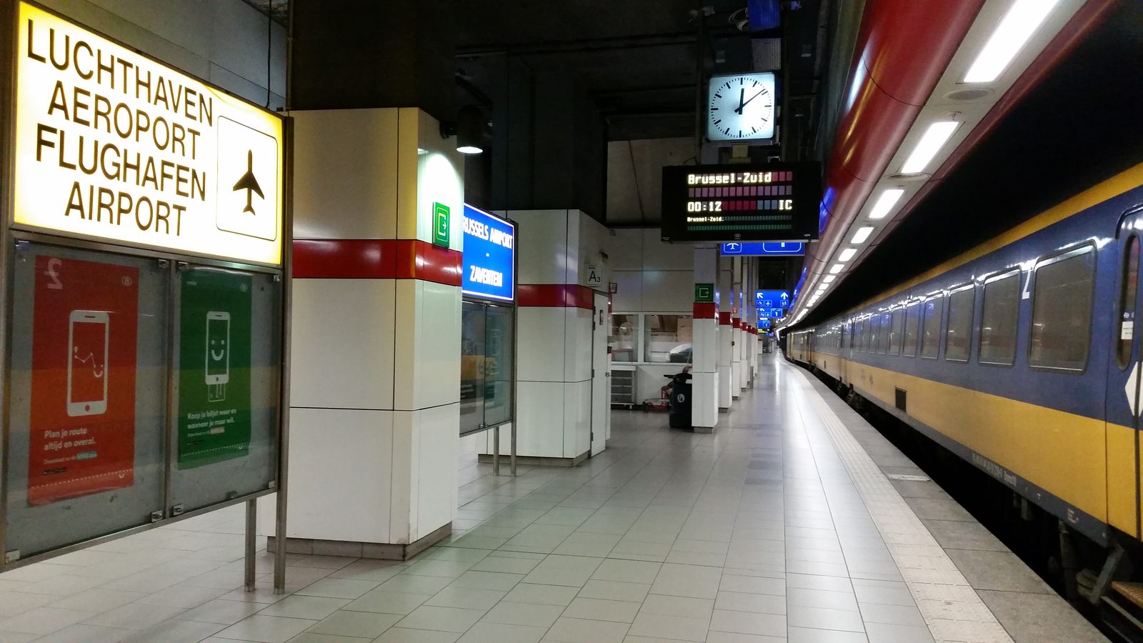 A train at the platform of Brussels Airport-Zaventem station, under the multilingual Airport sign