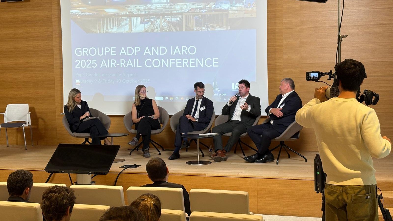 A panel on stage at the Groupe ADP and IARO 2025 Air-Rail Conference, with the conference title on the screen behind